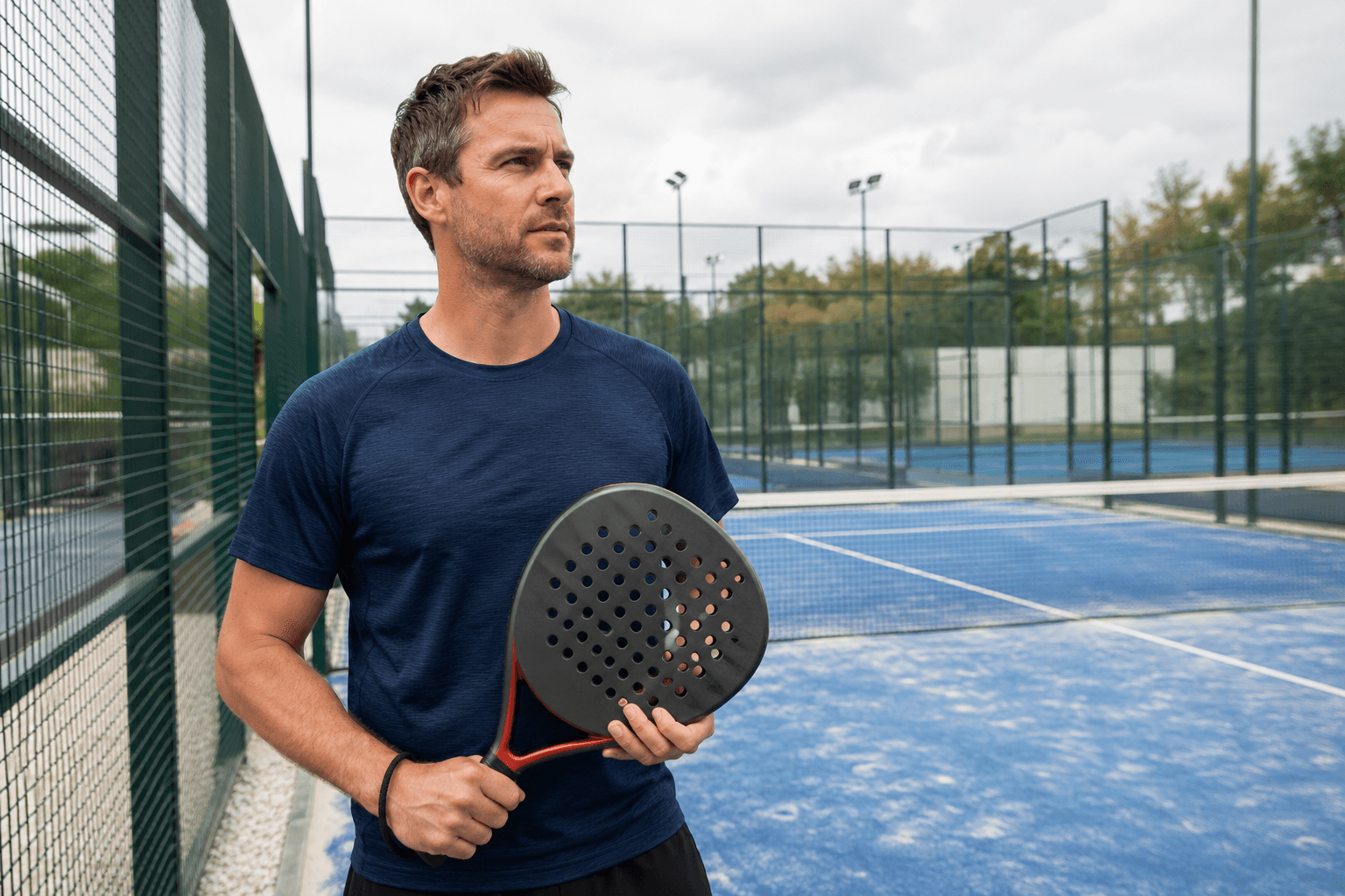 Player holding one of the best padel rackets under £100 beside a UK padel court